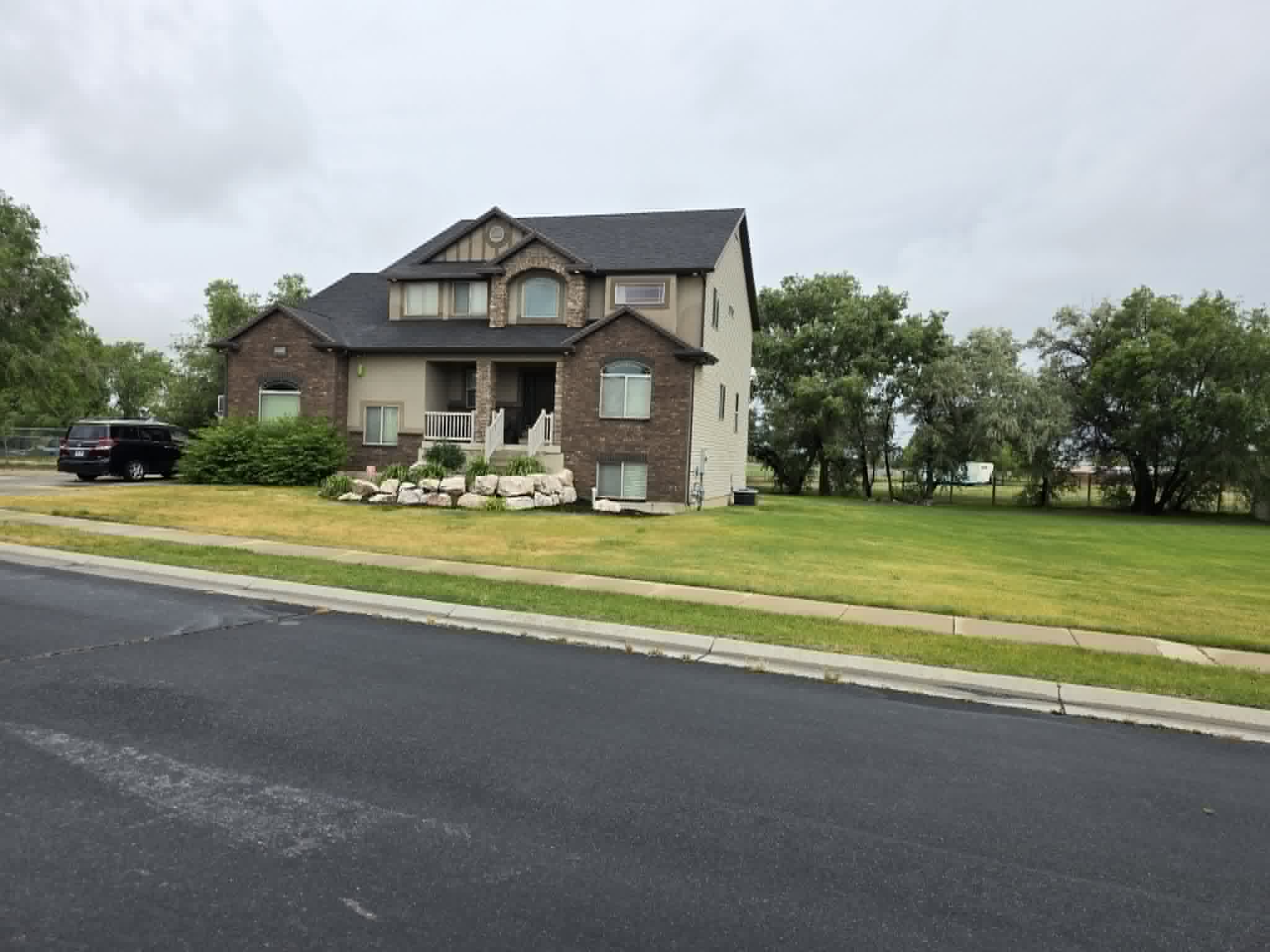 Two-story residence featuring brick and stucco exterior, arched windows, covered front porch, and a stone-edged garden bed