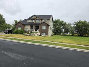 Two-story residence featuring brick and stucco exterior, arched windows, covered front porch, and a stone-edged garden bed