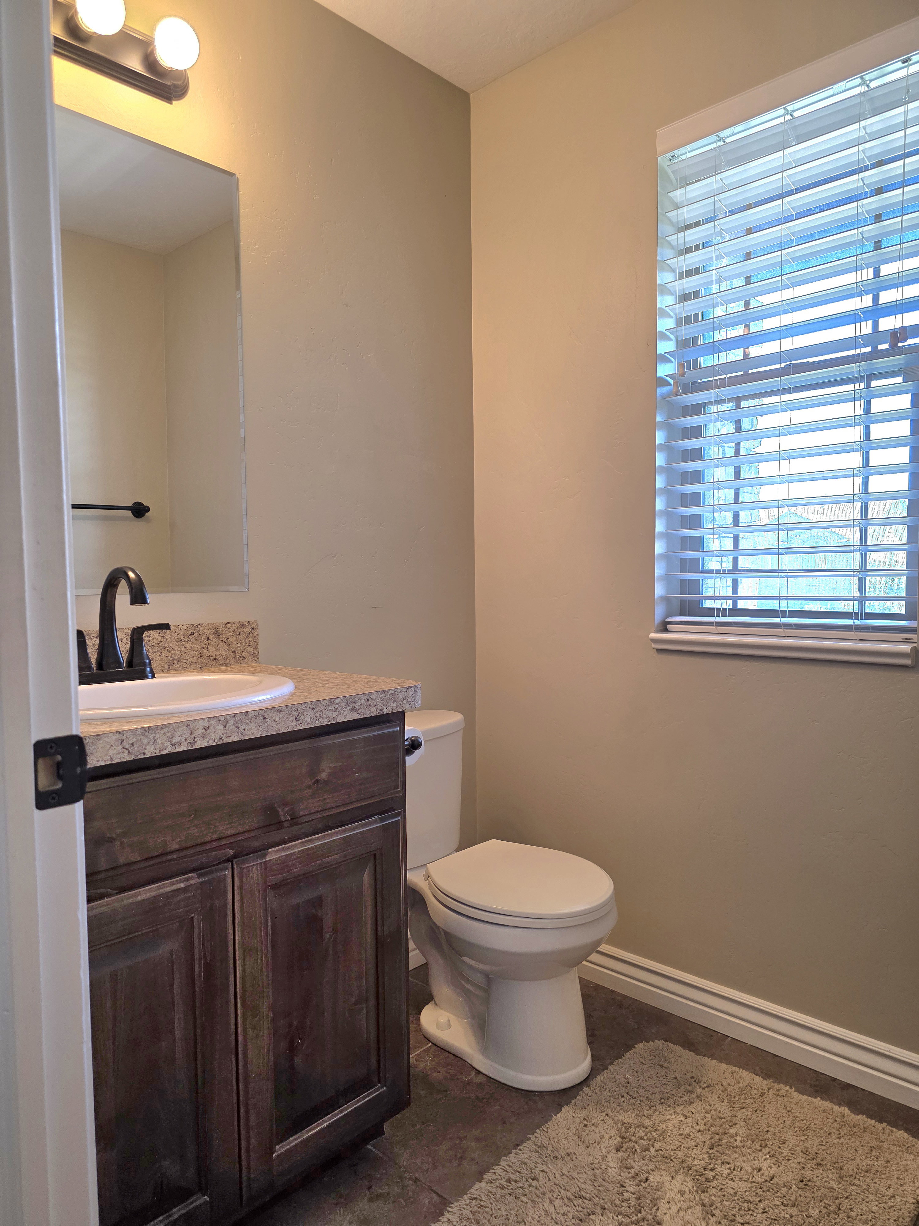 Bathroom featuring a dark wood vanity with a light-colored countertop, an undermount sink, and a black-finish faucet