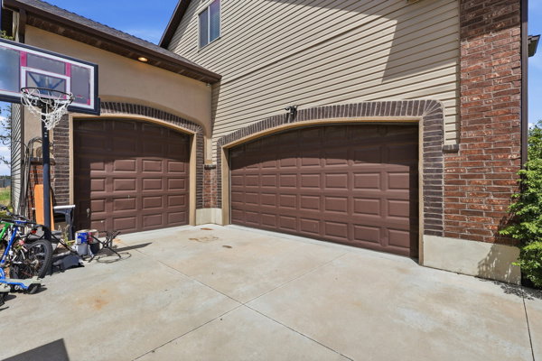 Two brown panel garage doors with brick archways and siding exterior