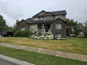 Two-story residence featuring a brick and stucco facade with stone accents, dark shingle roof, and multiple window styles