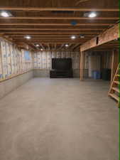 Unfinished basement with concrete flooring, exposed wood joists, recessed lighting, and insulated exterior walls