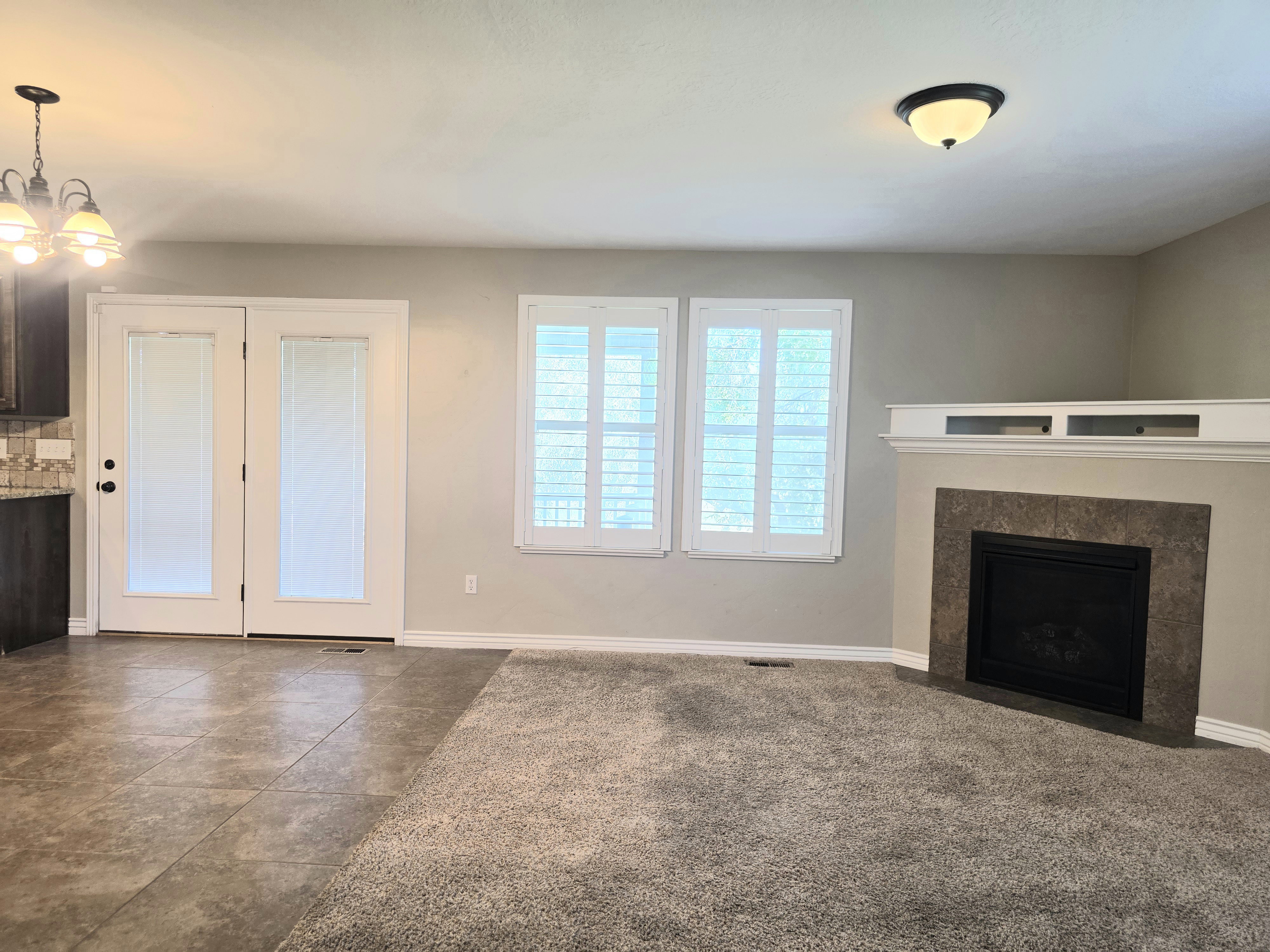 Living area featuring a fireplace with a stone surround, a white mantel, and built-in shelving