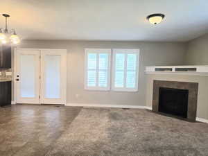 Living area featuring a fireplace with a stone surround, a white mantel, and built-in shelving