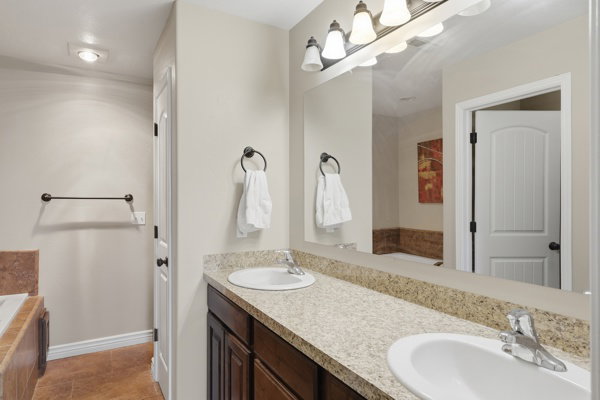 Double vanity with integrated sinks, granite-look countertop, and wood-finish cabinetry