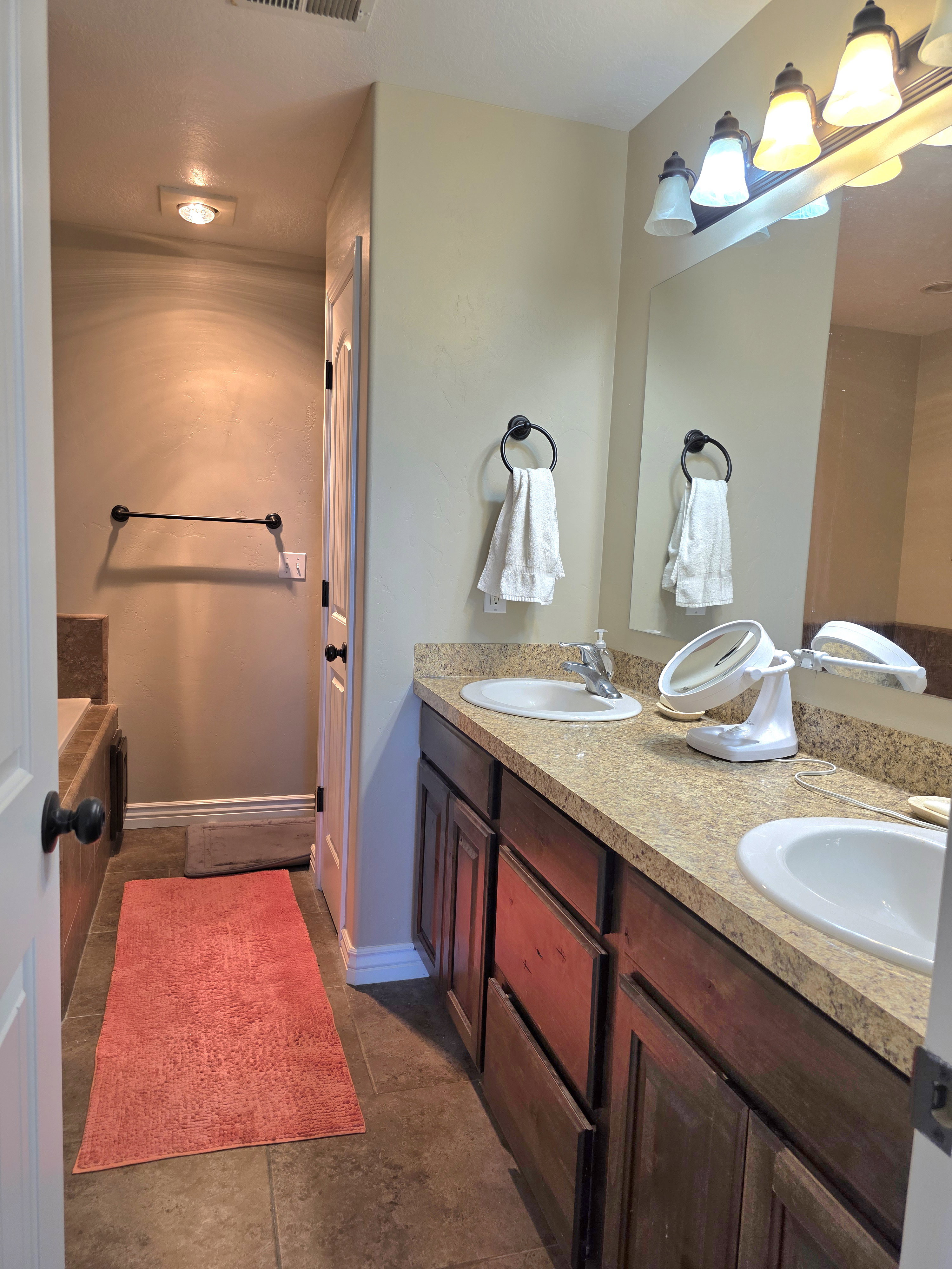 Bathroom vanity featuring dual under-mount sinks, a stone-finish countertop, and dark wood-finish cabinetry