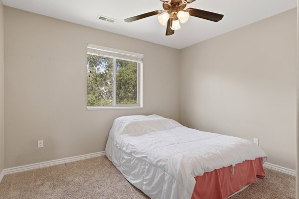 Carpeted room featuring a window with natural light, a ceiling fan with integrated lighting, and neutral-toned walls