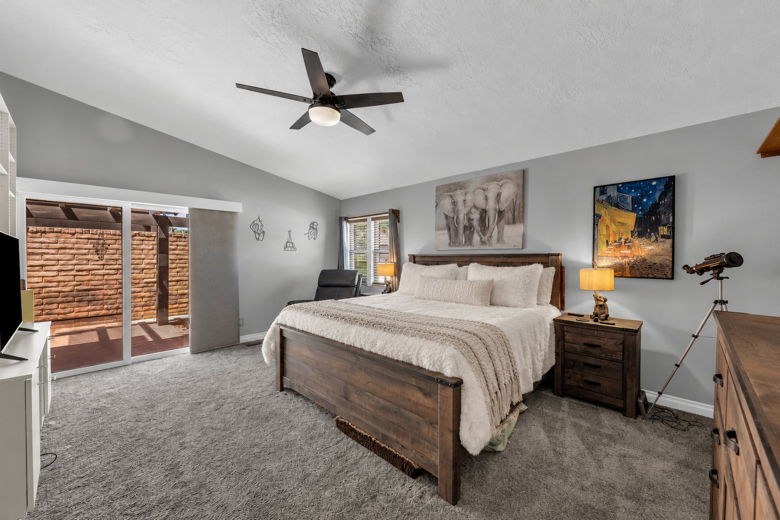 Spacious room featuring newer carpet, 3-tone paint, a vaulted ceiling, door to patio, with window covering.
