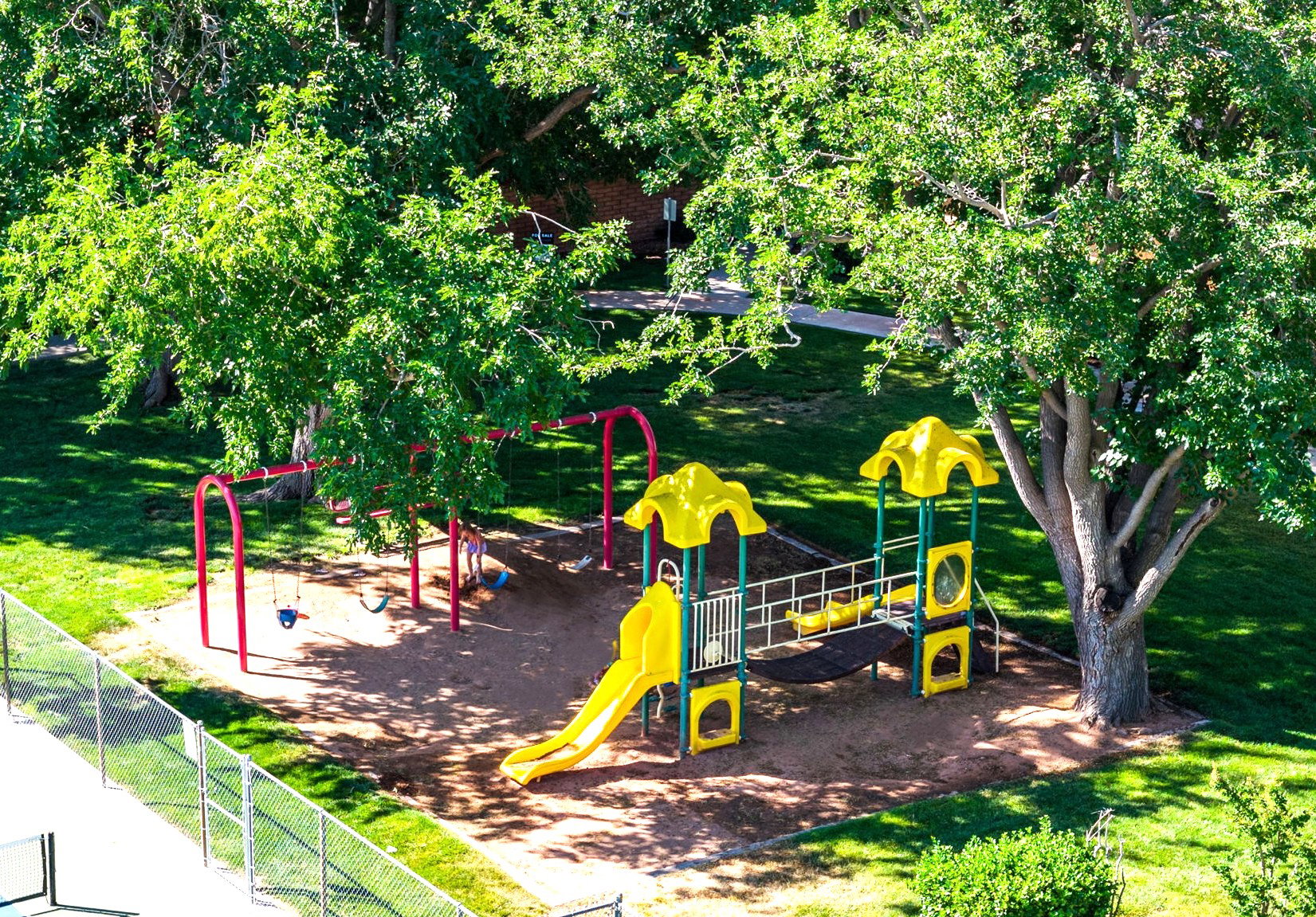 Outdoor playground area featuring a multi-level structure with slides and a separate swing set