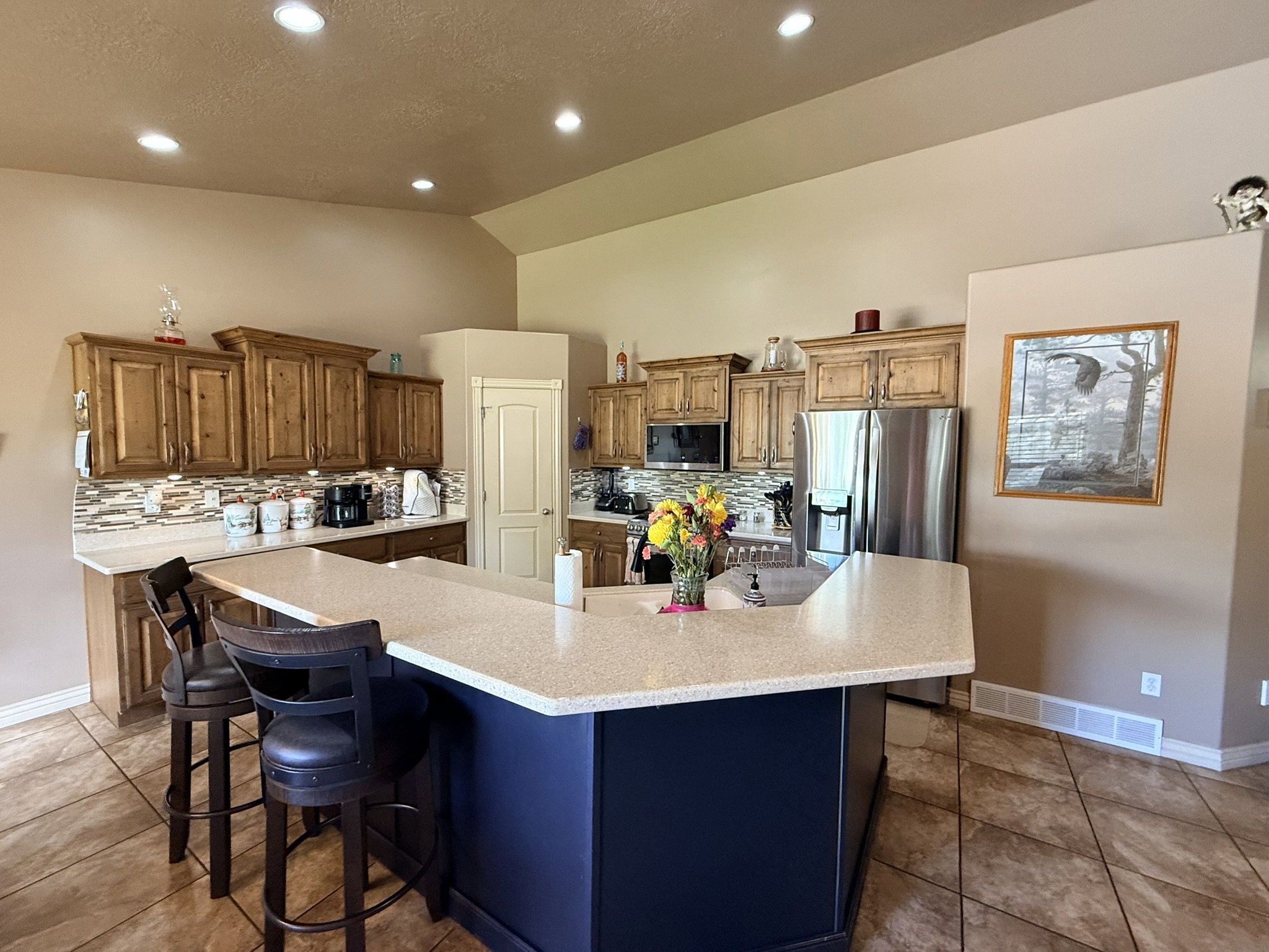 Kitchen featuring wood cabinetry, stone-look countertops, a multi-tone tile backsplash, stainless steel appliances, and recessed lighting