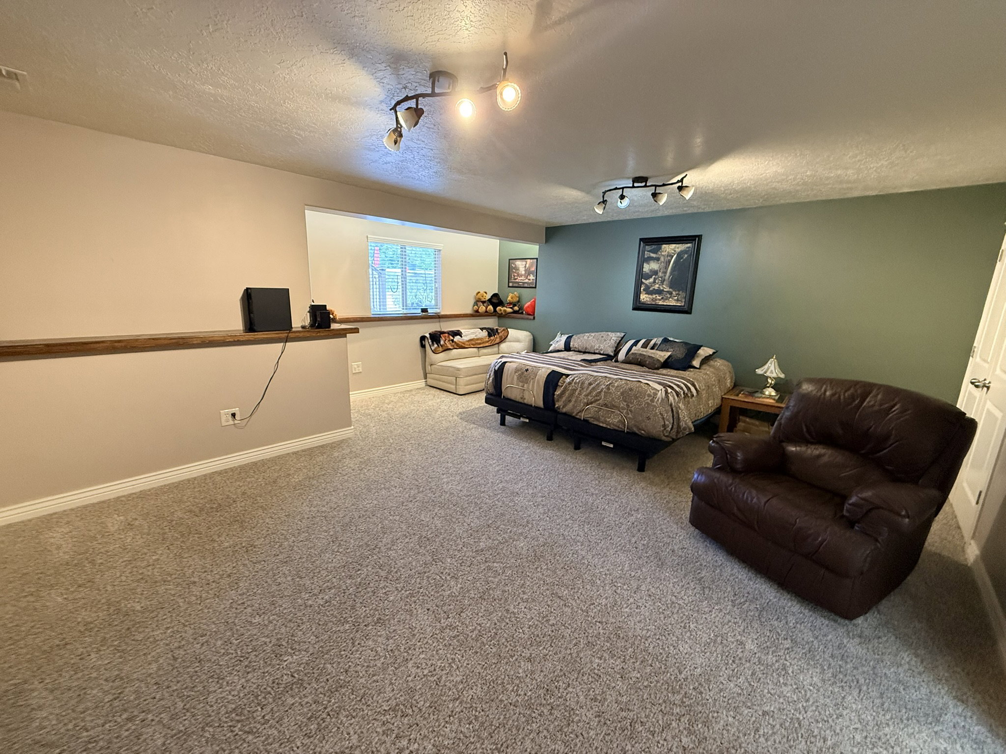Spacious room featuring neutral carpet flooring and a partial divider wall with a wood-finish top