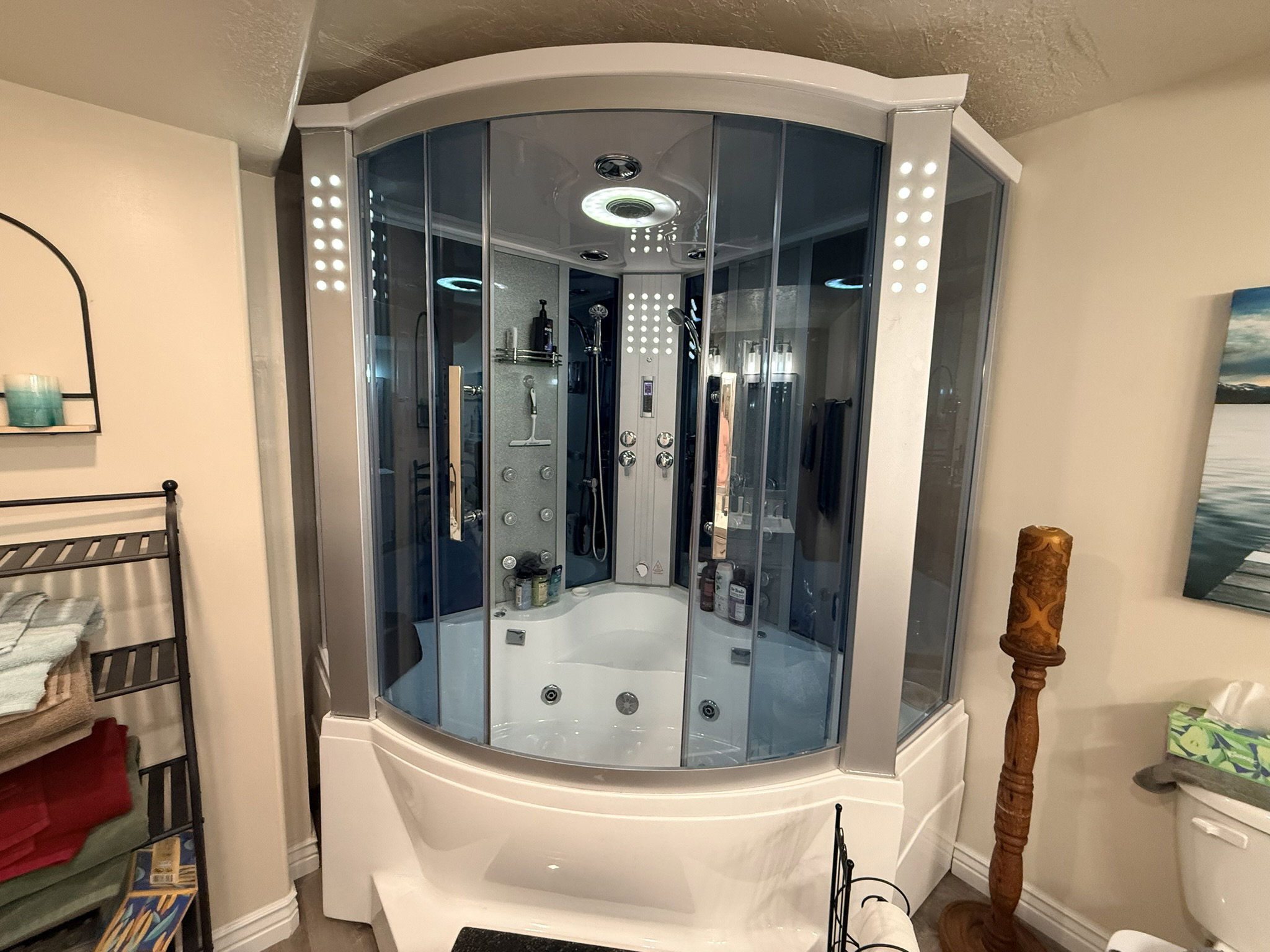 Corner shower enclosure featuring clear glass panels, an integrated soaking tub, and a multi-jet shower system