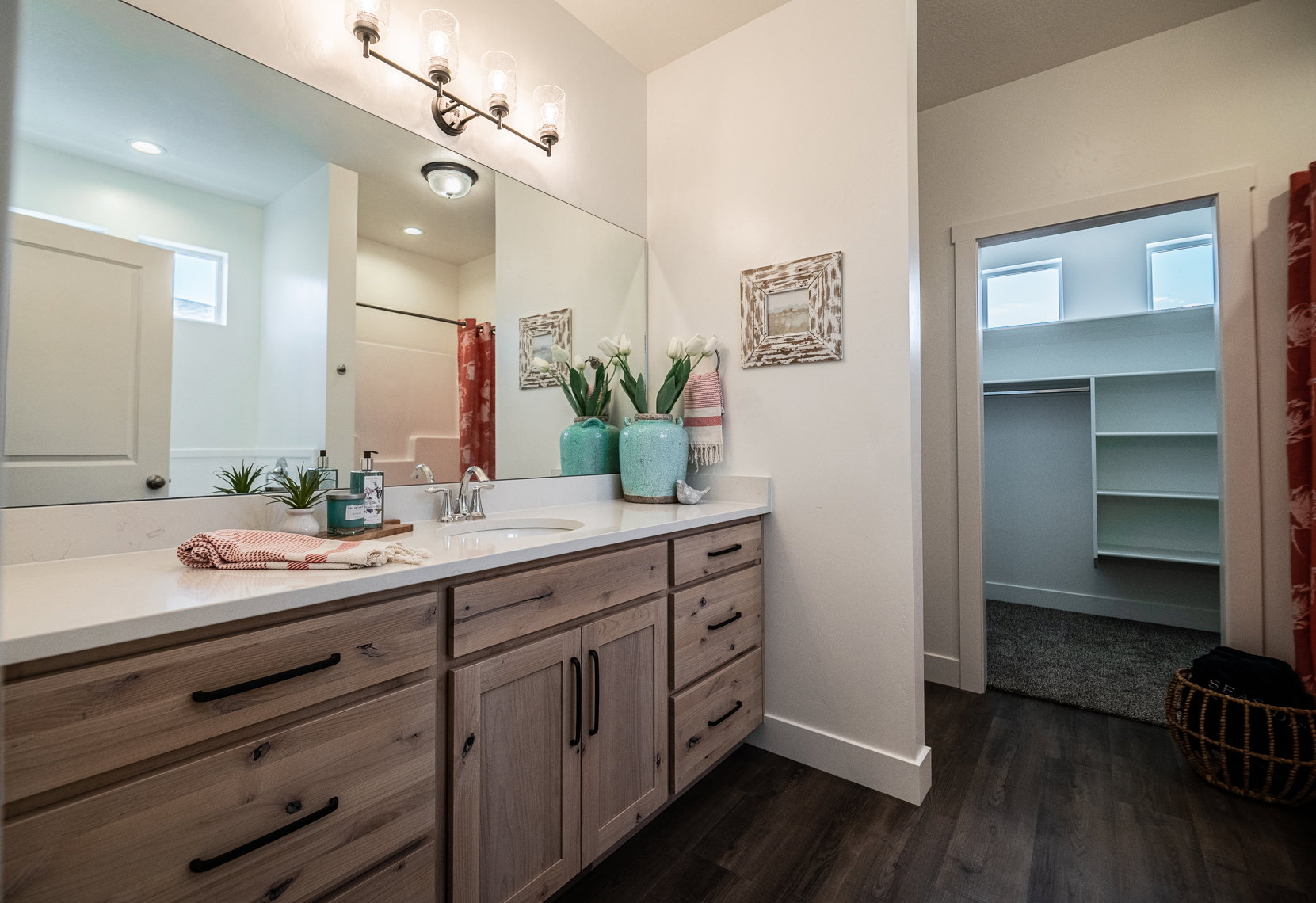 Bathroom vanity featuring wood-finish cabinetry with black hardware, a light-colored countertop, and an integrated sink