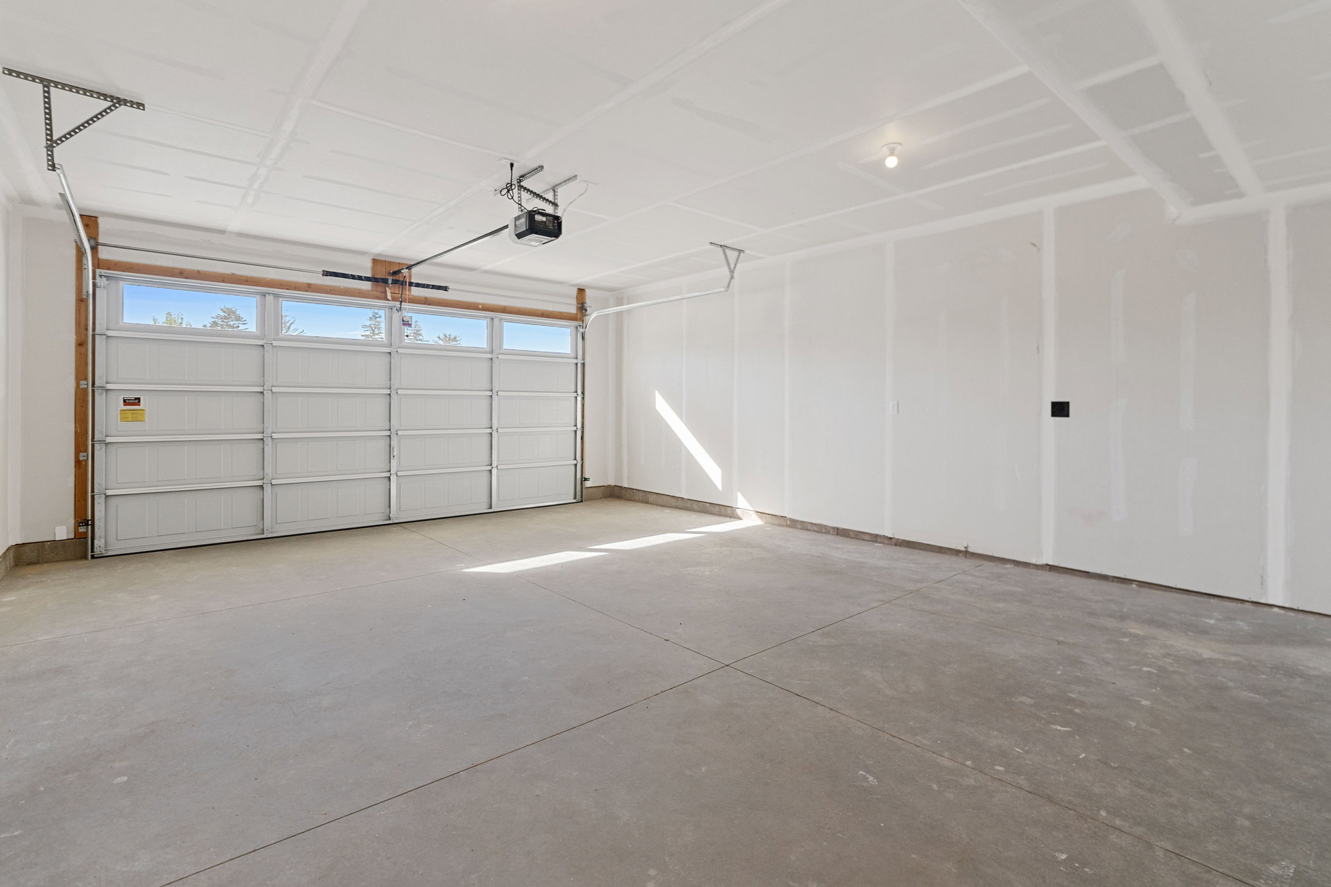 Spacious garage featuring a concrete floor, an automatic garage door opener, and an overhead garage door with upper-level windows