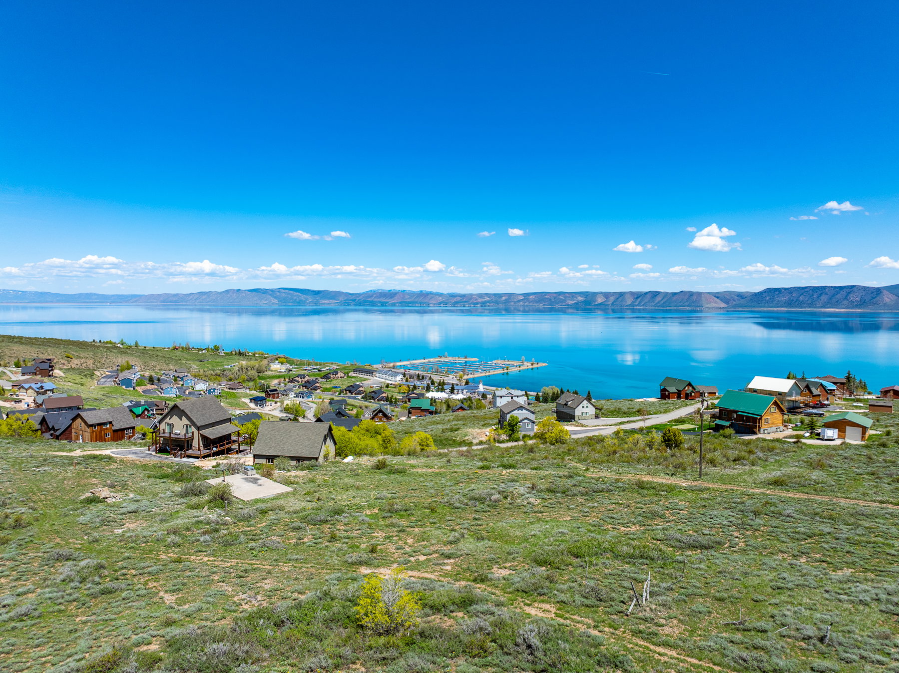 Expansive hillside property featuring a community of homes, a large body of water, and distant mountains