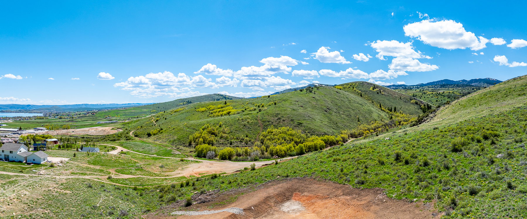 Expansive hillside lot with partial lake visibility, surrounded by green rolling hills and distant mountains