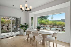 Dining area featuring light wood-finish flooring, a large picture window, and a sliding glass door.