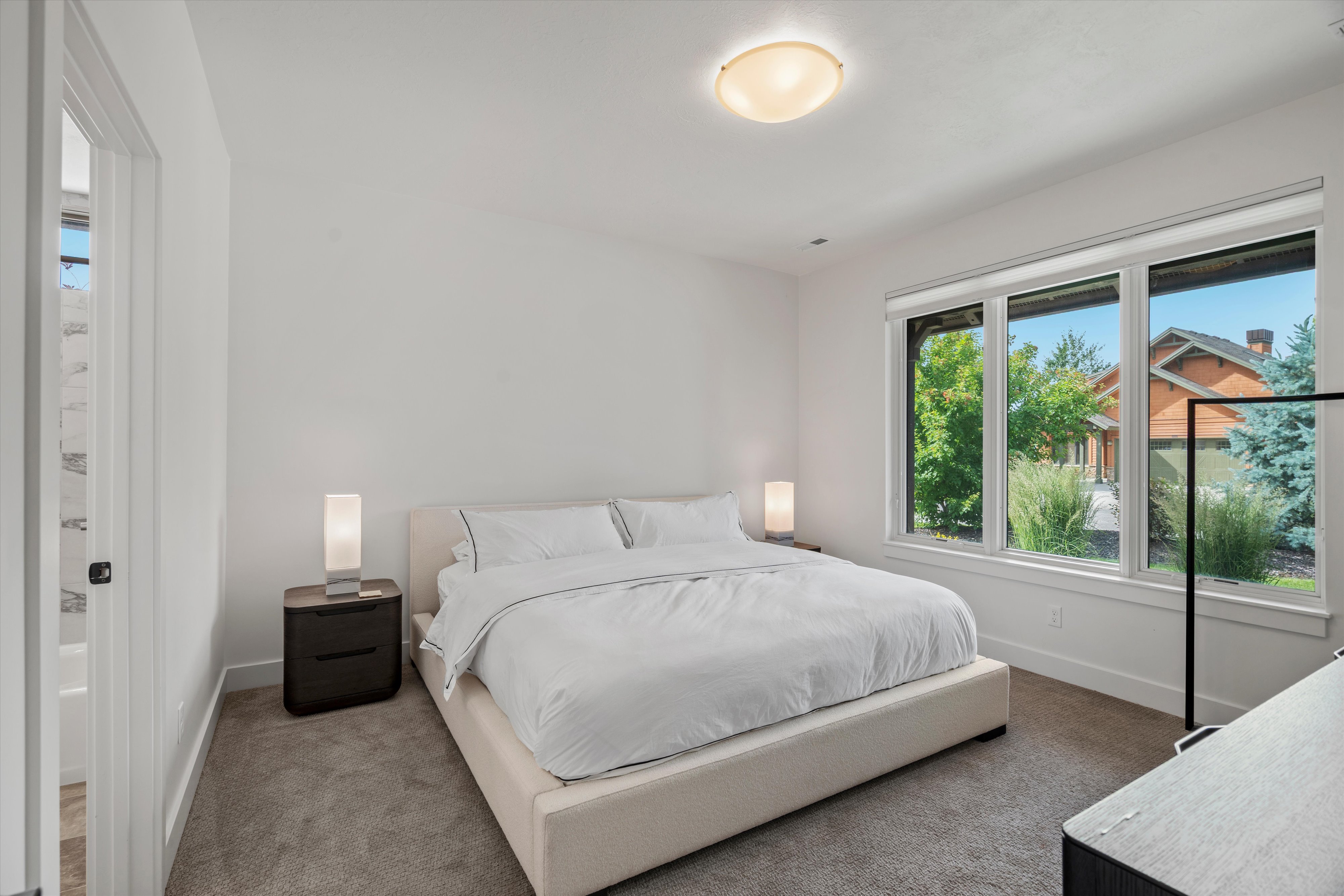 Guest suite featuring plush carpeting, a large three-panel window, and an en-suite bathroom.