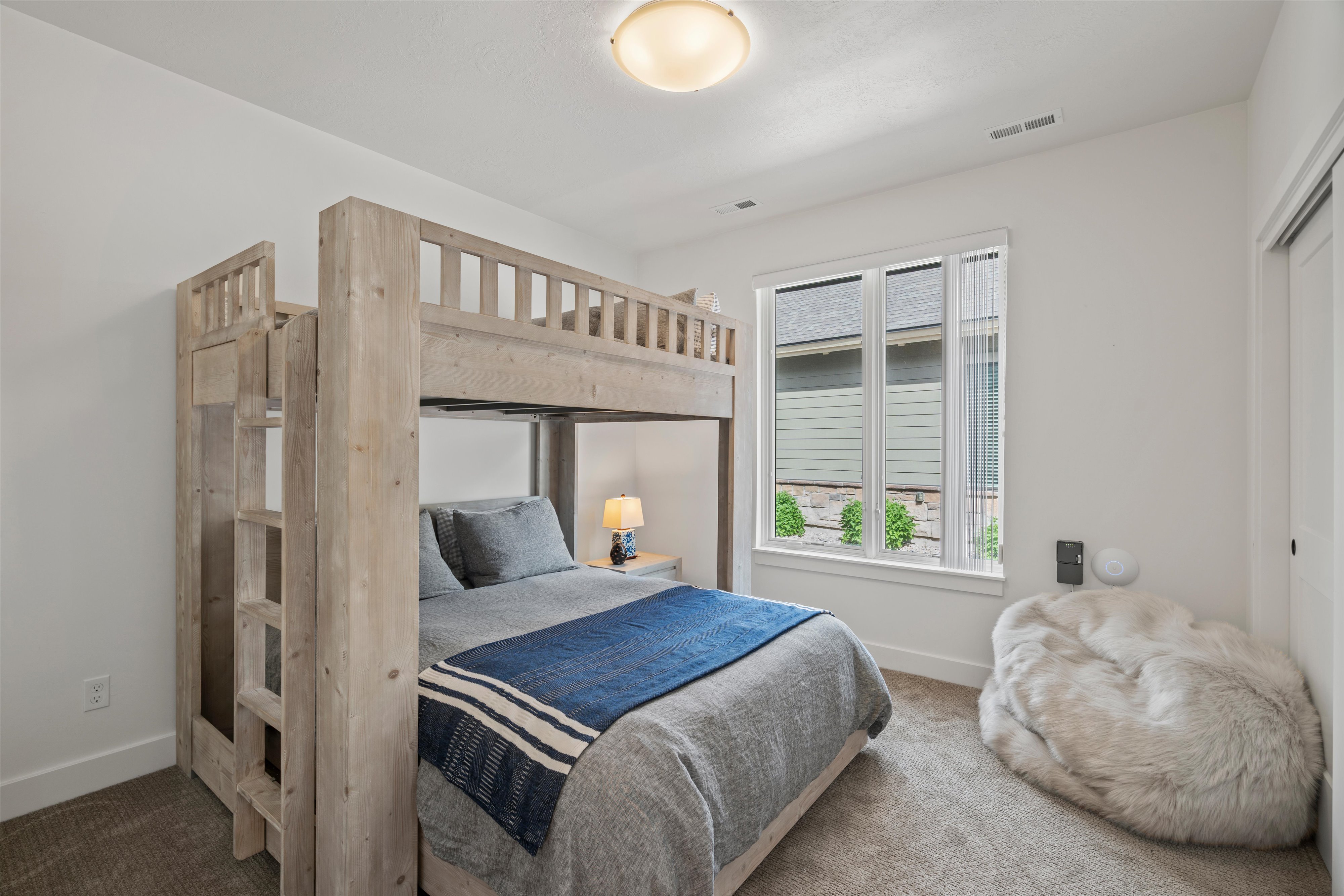 Bedroom featuring high-end bunk bed, white walls, a large window, and carpet flooring
