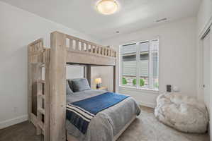 Bedroom featuring high-end bunk bed, white walls, a large window, and carpet flooring