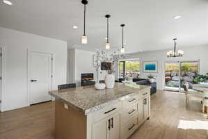 Large kitchen island featuring a light-toned granite countertop and cream-colored cabinetry with dark hardware.