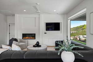 Living space featuring a built-in fireplace, a ceiling fan, recessed lighting, a large window, and built-in cabinetry.