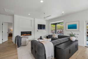 Spacious living area featuring light wood-finish flooring, recessed lighting, and a modern linear fireplace.