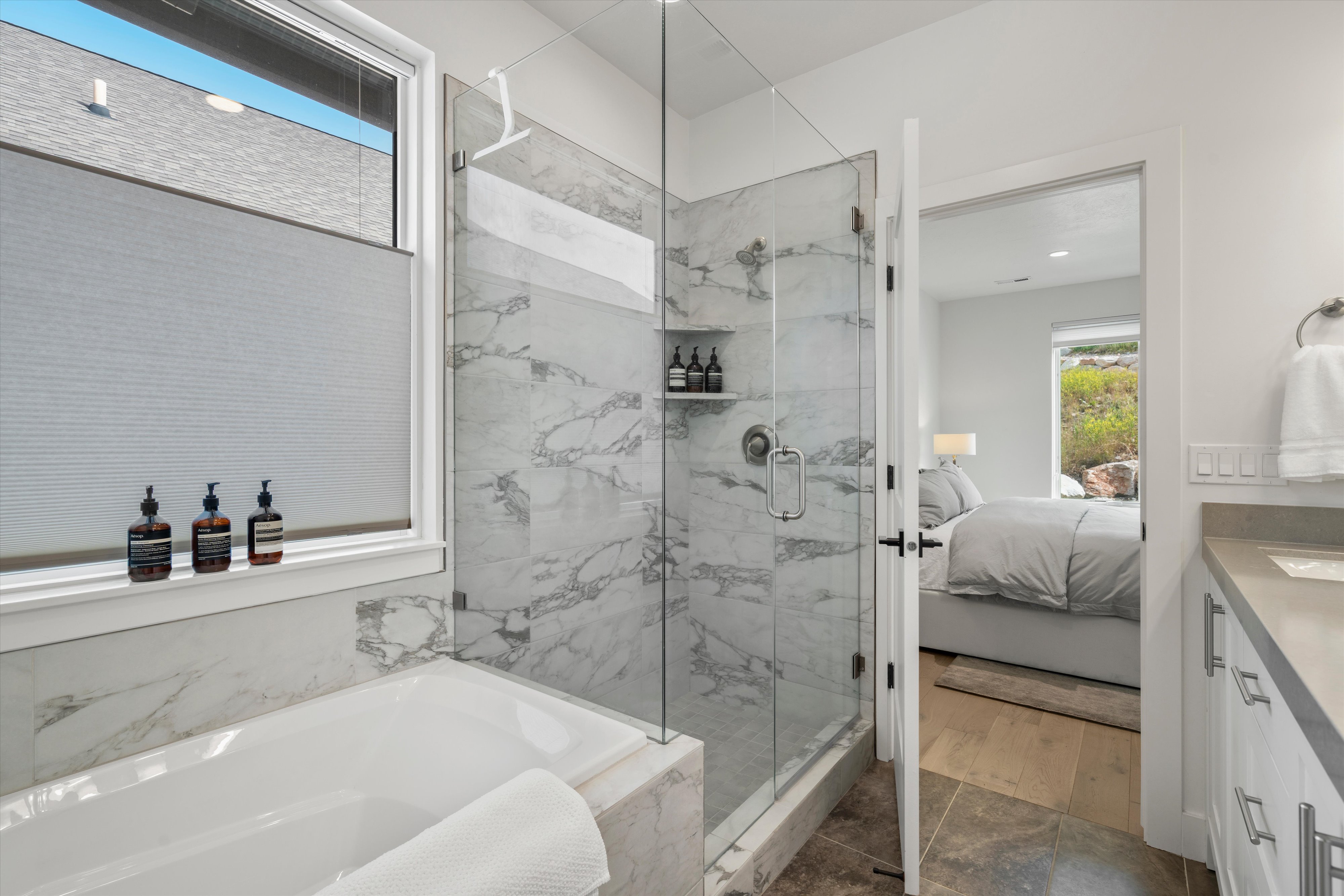 Contemporary bathroom featuring a large soaking tub, glass-enclosed shower with tiled walls, and a window with lots of natural light.