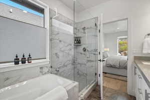 Contemporary bathroom featuring a large soaking tub, glass-enclosed shower with tiled walls, and a window with lots of natural light.