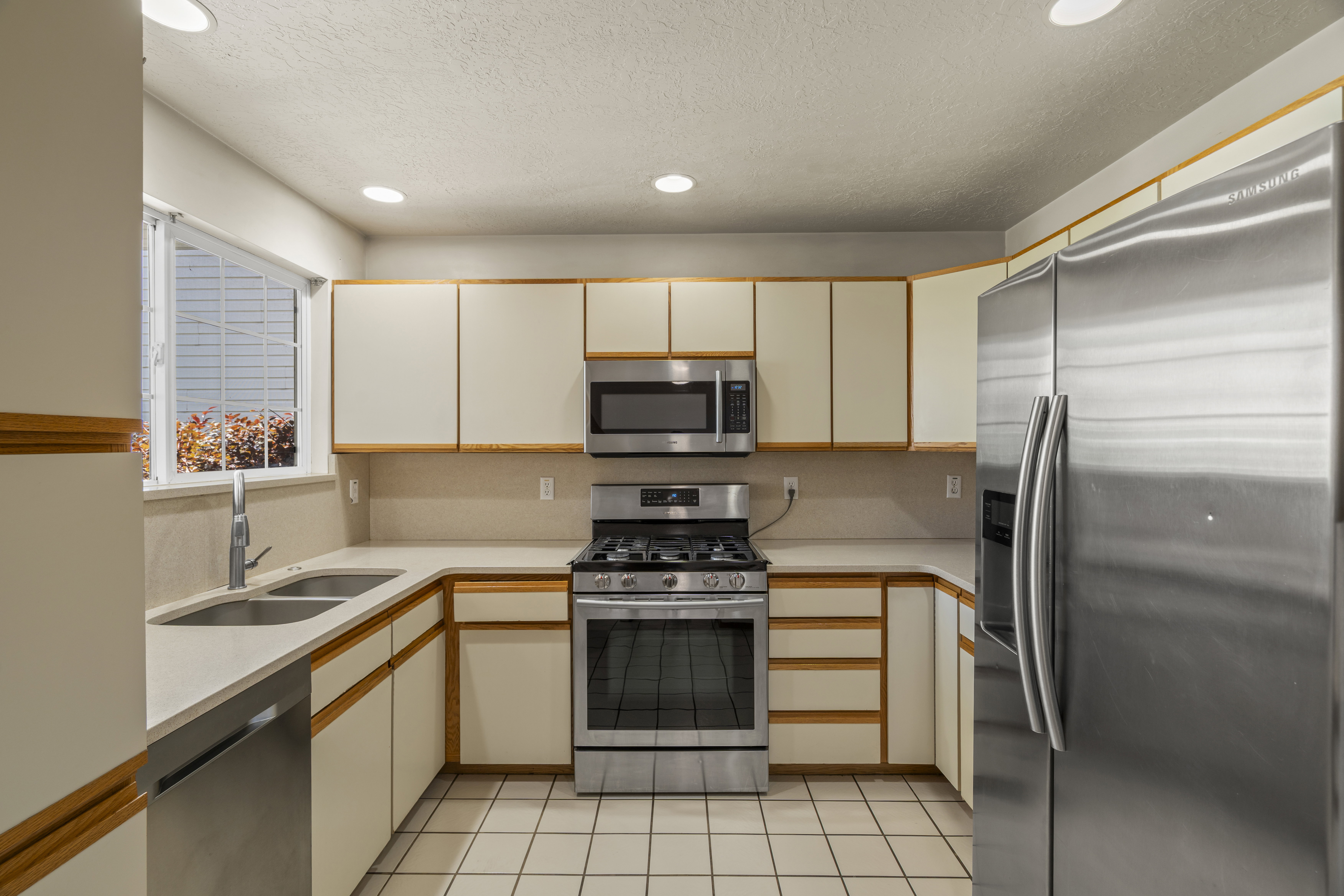Kitchen featuring stainless steel appliances, light-toned cabinetry, light countertops, and recessed lighting