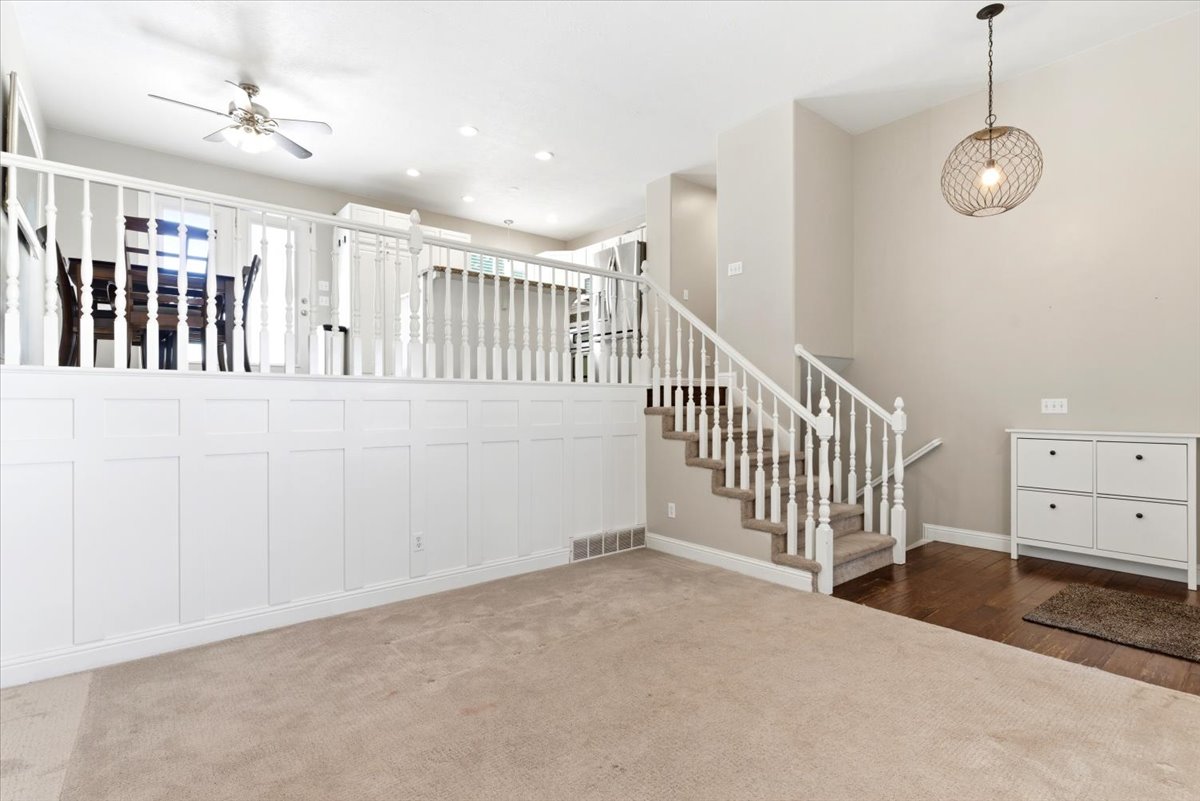 Split-level entry with wood-finish flooring, carpeted stairs, and a white baluster railing