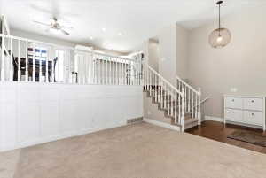 Split-level entry with wood-finish flooring, carpeted stairs, and a white baluster railing