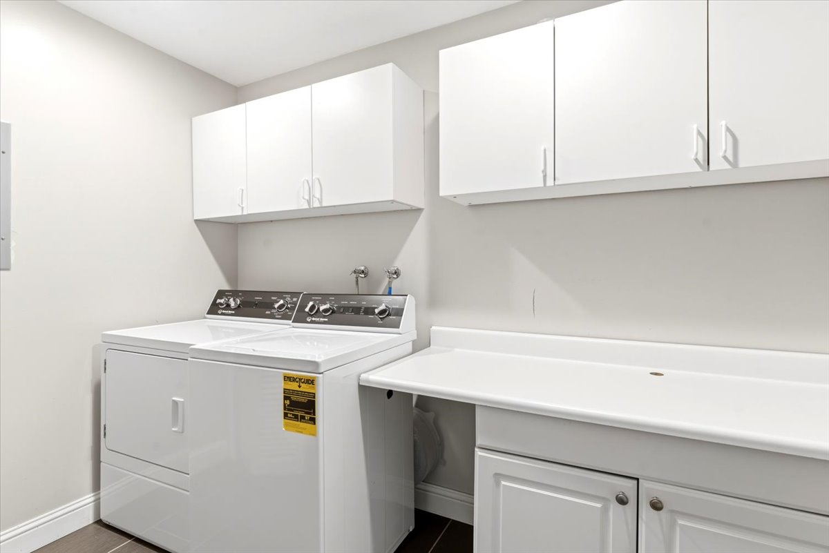 Functional laundry area featuring white cabinetry, a built-in countertop, and dark floor tiles