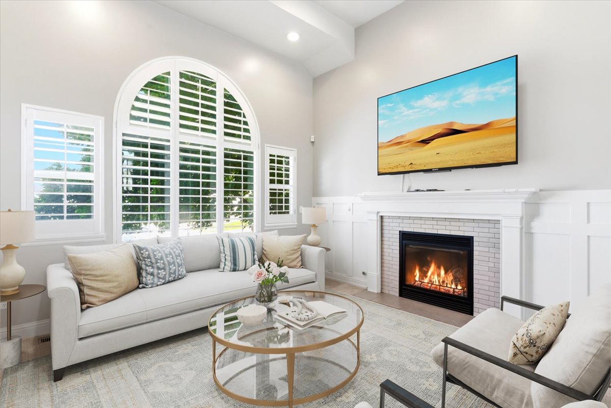 Living room featuring an arched window with plantation shutters, a white paneled fireplace with a white brick surround, and light wood-finish flooring
