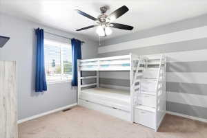 Spacious room featuring neutral carpet flooring, a window with horizontal blinds, and a ceiling fan with integrated lighting