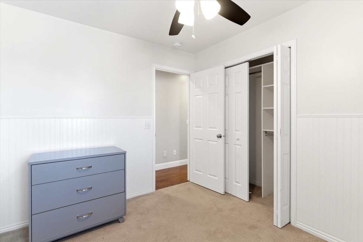 Room with light beige carpet flooring and white beadboard wainscoting