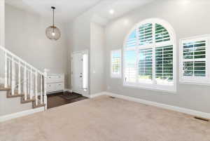 Two-story entryway featuring an arched window with white plantation shutters, a complementary side window, and a white front door with a sidelight