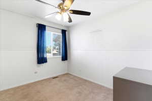 Interior room featuring a ceiling fan with integrated lighting, a window with horizontal blinds, wainscoting along the lower walls, and carpet flooring