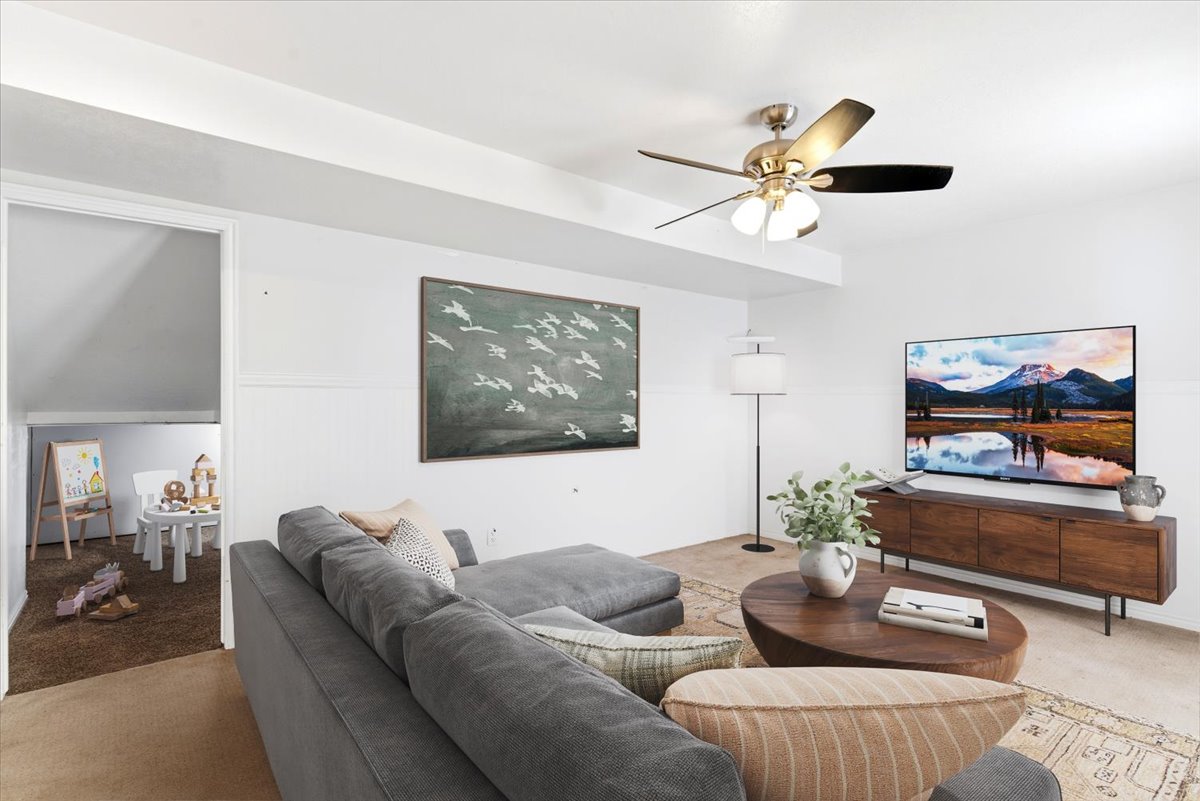 Living area featuring recessed ceiling beams, a ceiling fan with integrated lighting, and a wood-finish media console