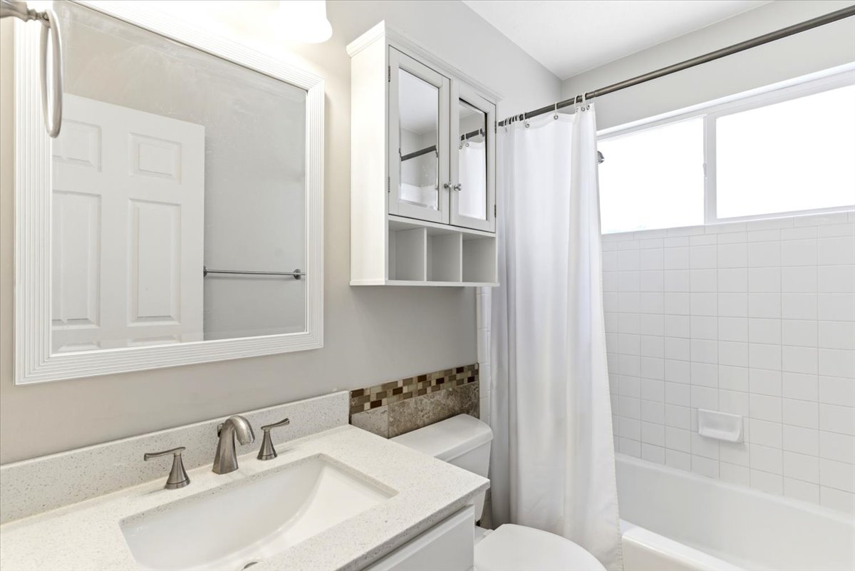 Bathroom featuring a vanity with an integrated sink, a speckled countertop, and a tiled backsplash