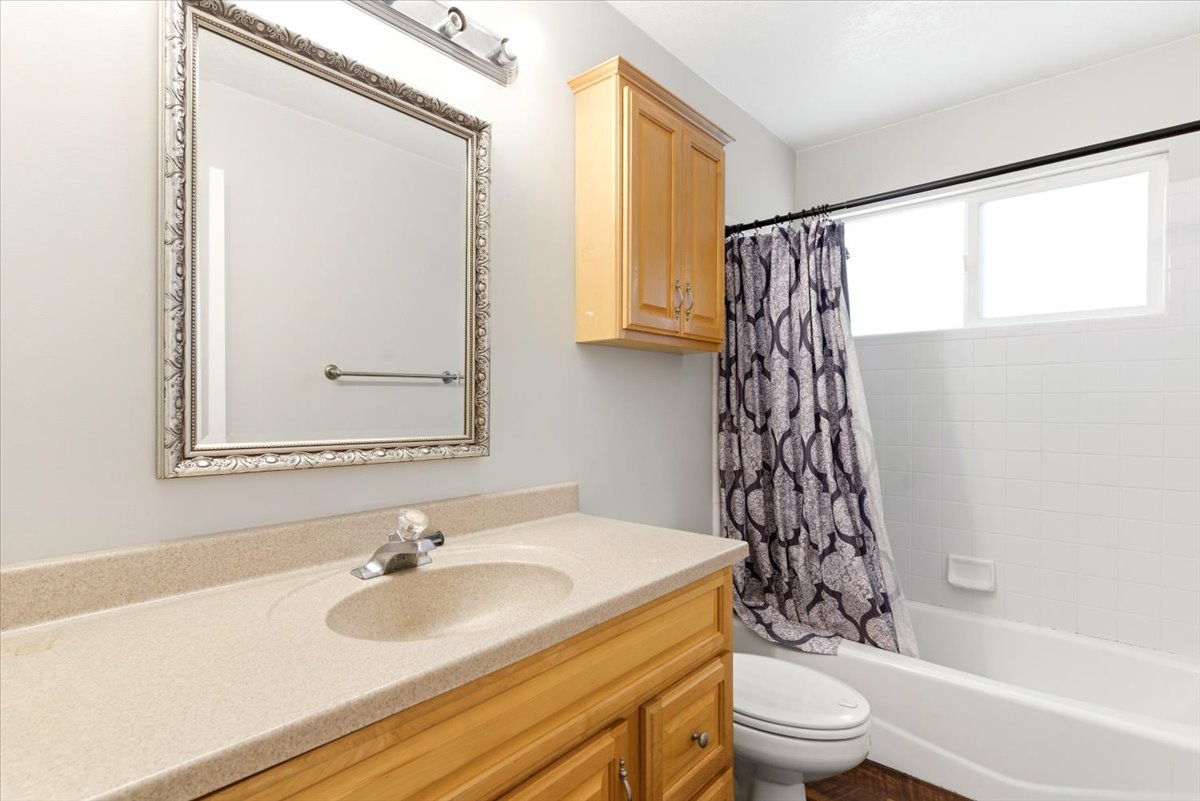 Bathroom featuring a light wood-finish vanity with an integrated sink and light speckled countertop