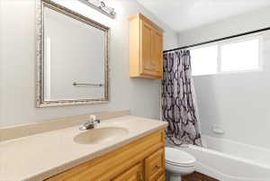 Bathroom featuring a light wood-finish vanity with an integrated sink and light speckled countertop