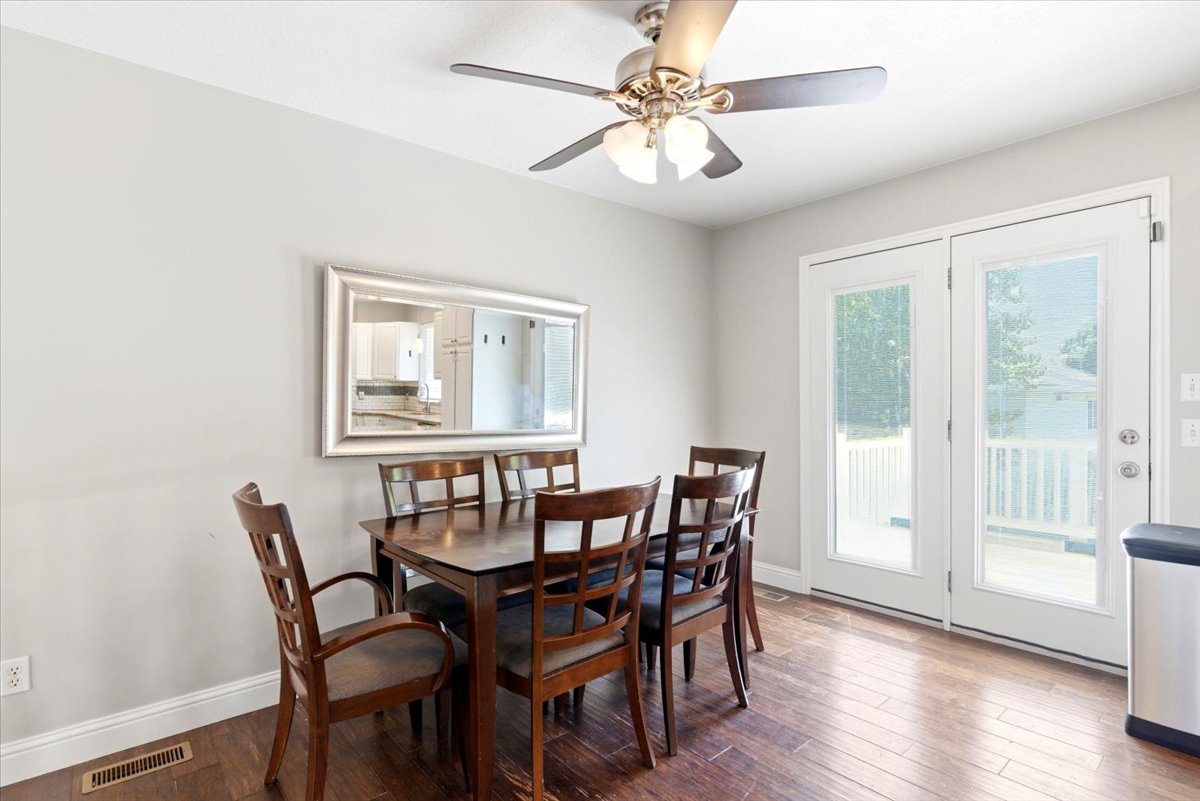 Dining area featuring wood-finish flooring, light gray walls, and a ceiling fan with integrated lighting