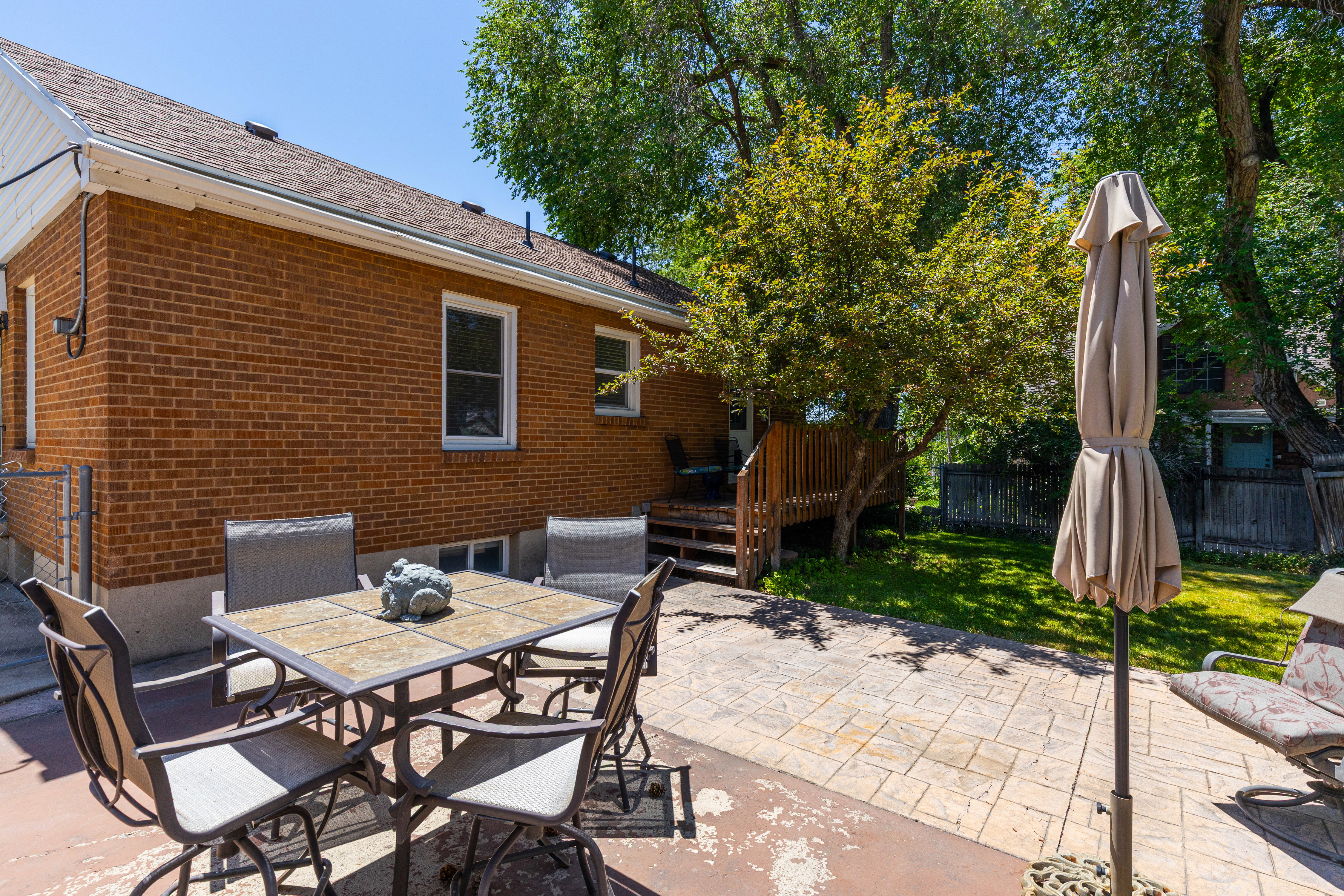 Brick exterior with multiple windows, a wood deck, and a stamped concrete patio