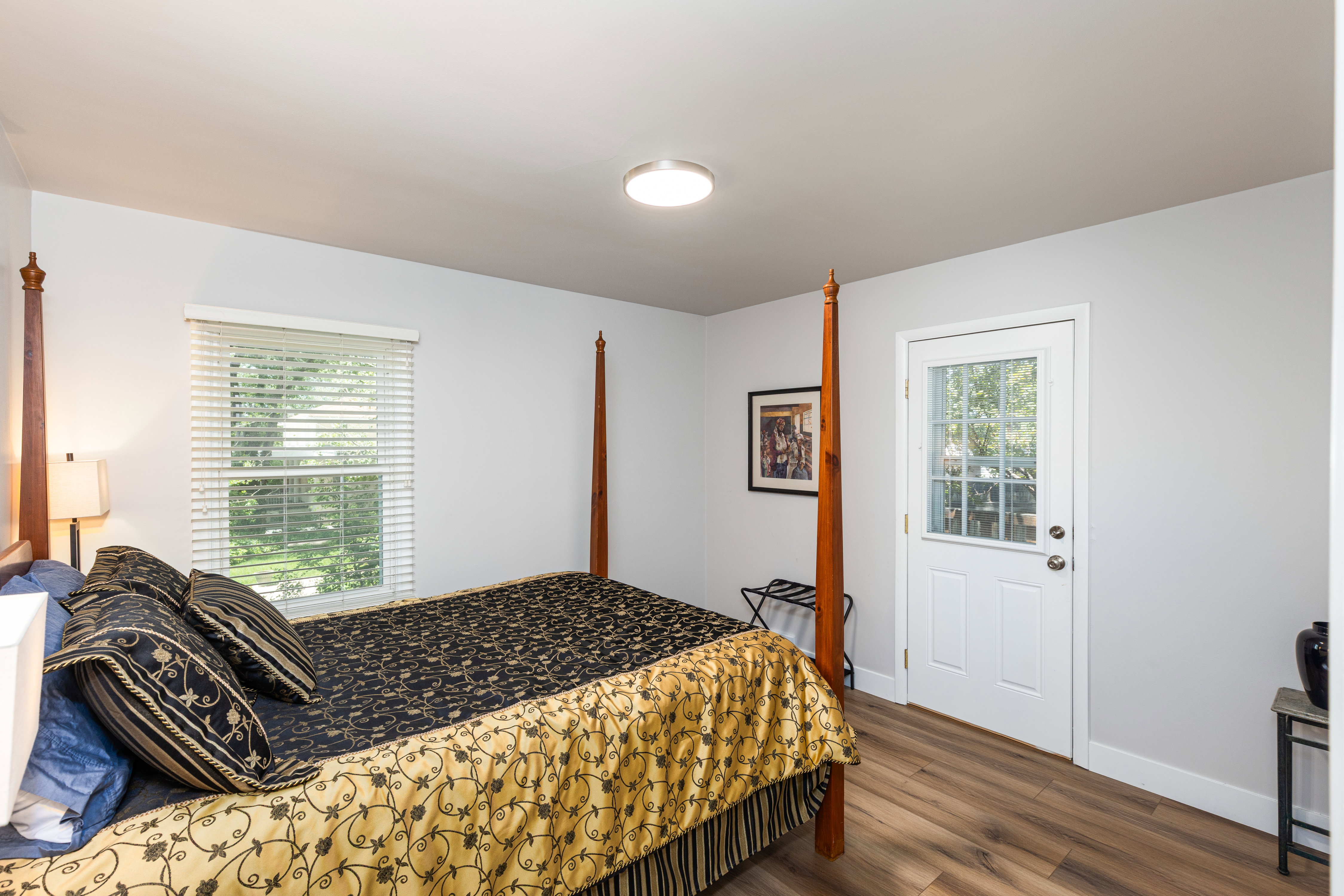 Room featuring wood-finish flooring, a contemporary ceiling light fixture, and a window with horizontal blinds