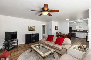 Open-concept living area featuring wood-finish flooring and a ceiling fan with integrated lighting