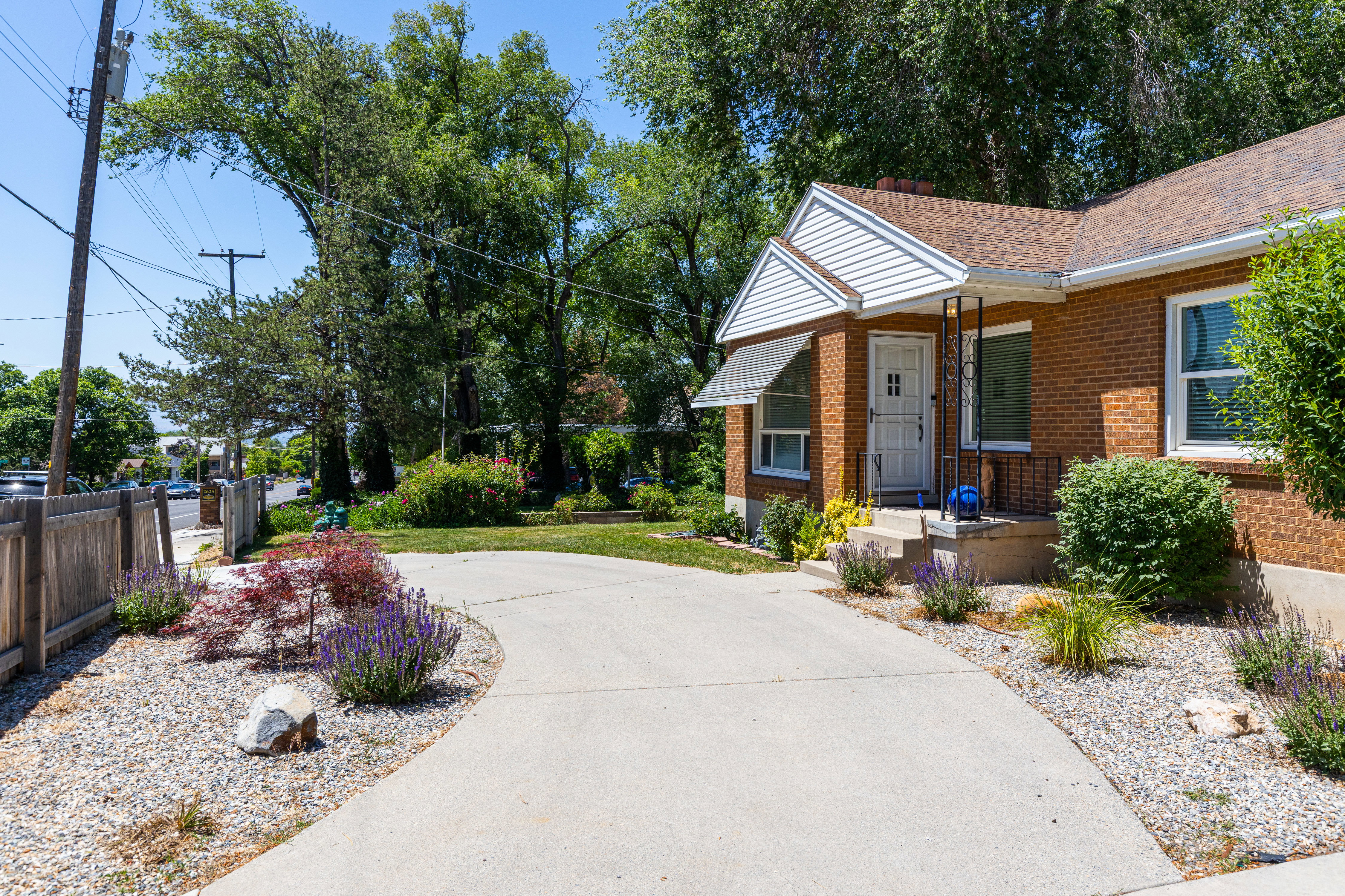 Brick exterior residence featuring a concrete driveway and mature trees