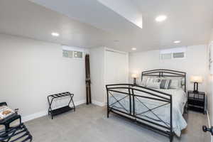 Carpeted bedroom featuring recessed lighting, a built-in closet with bi-fold doors, and a window with a roller shade