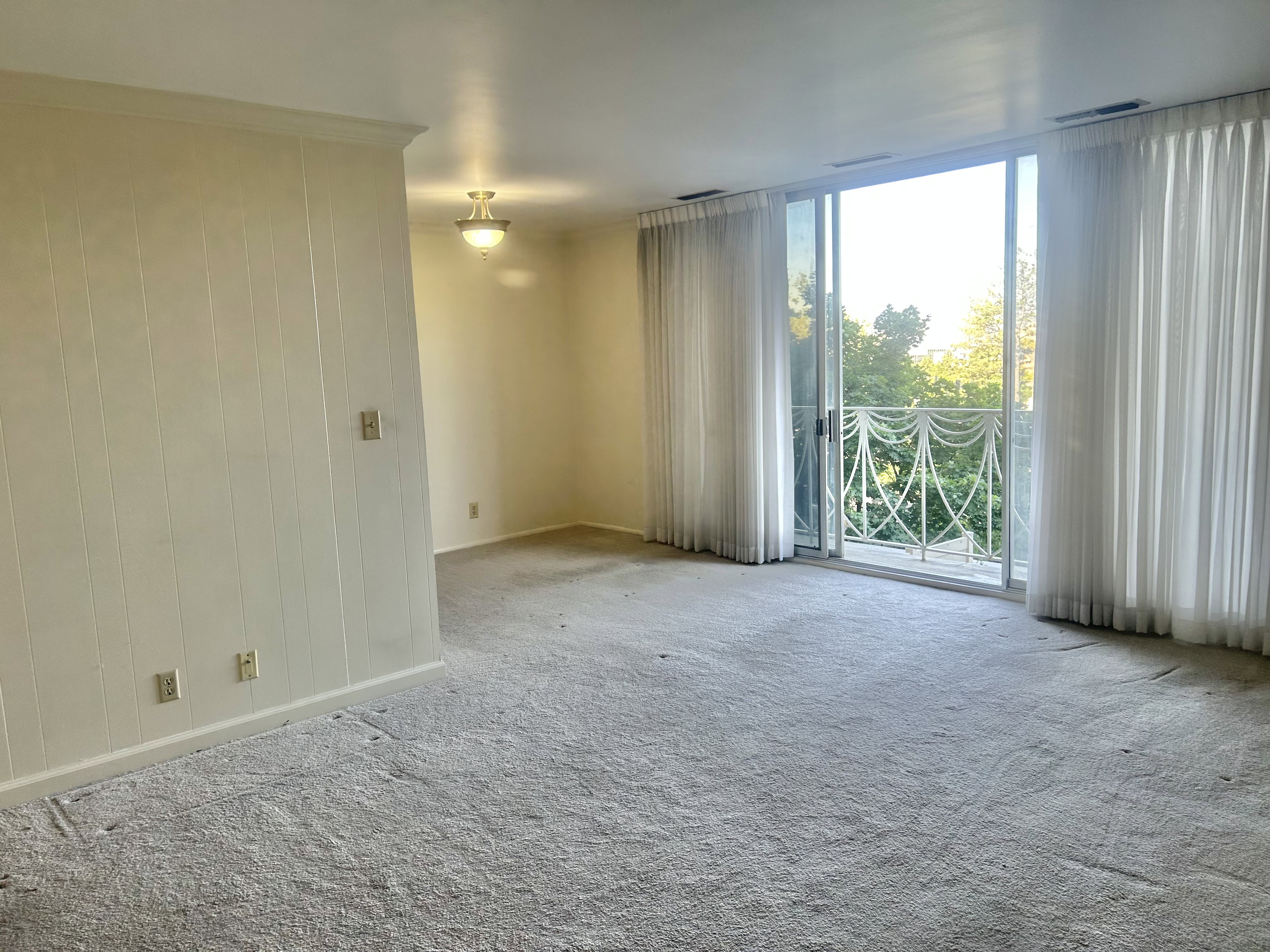 Spacious interior with neutral carpeting and vertical wall paneling