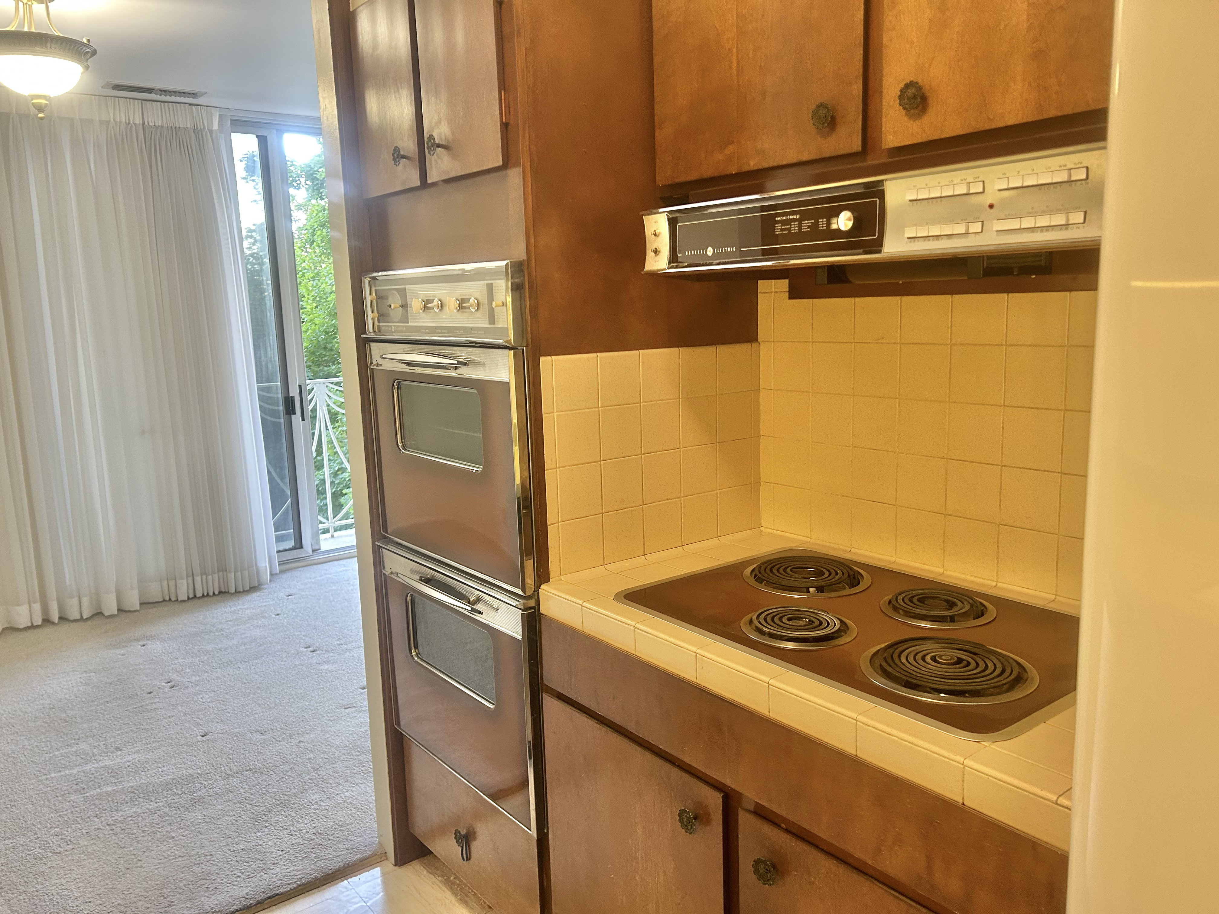 Kitchen featuring wood cabinetry, integrated double wall ovens, built-in cooktop, and a tiled backsplash